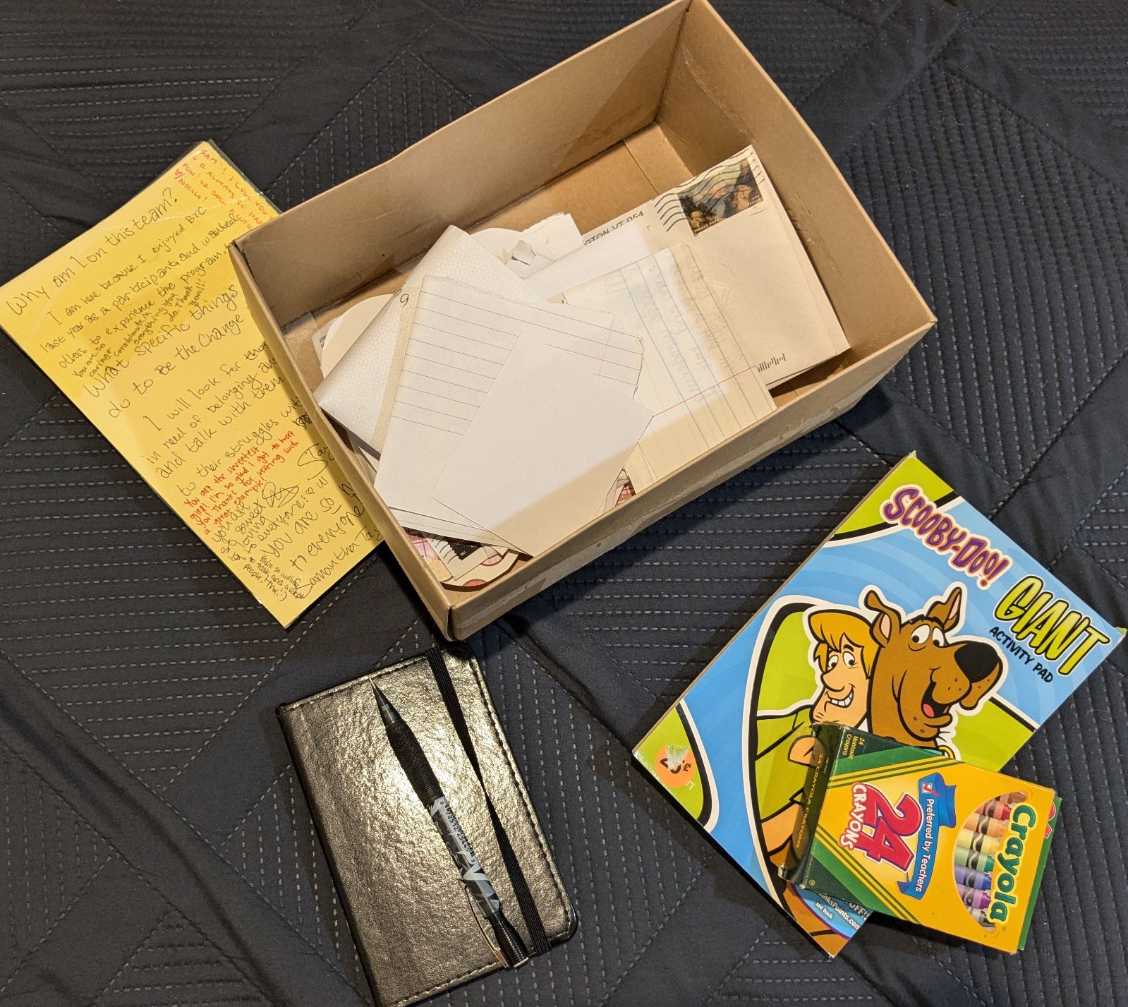 Picture of my mental health crisis kit with a journal, pencil, coloring book, crayons, and a box filled with letters.